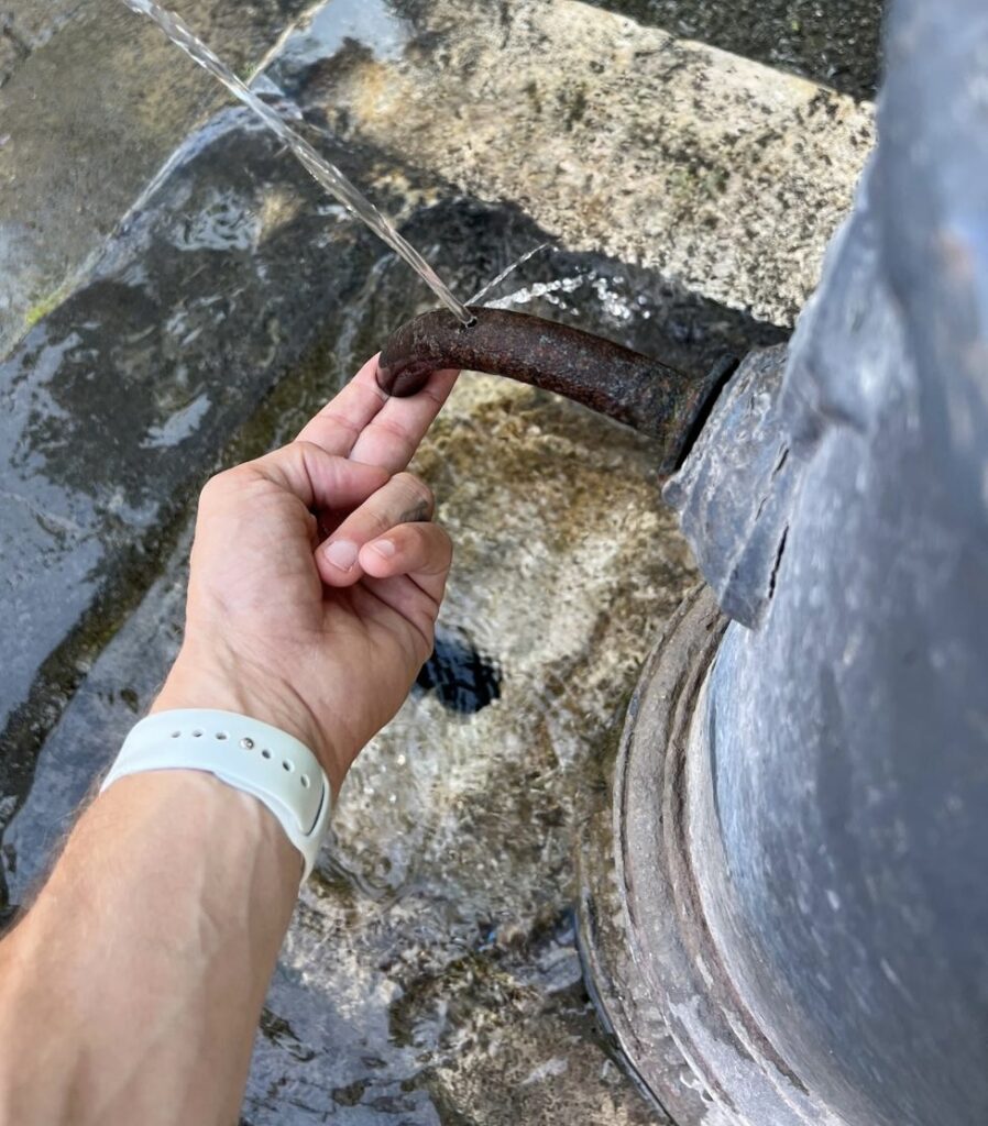 Hand blocking a nasone spout with water spurting from the top hole