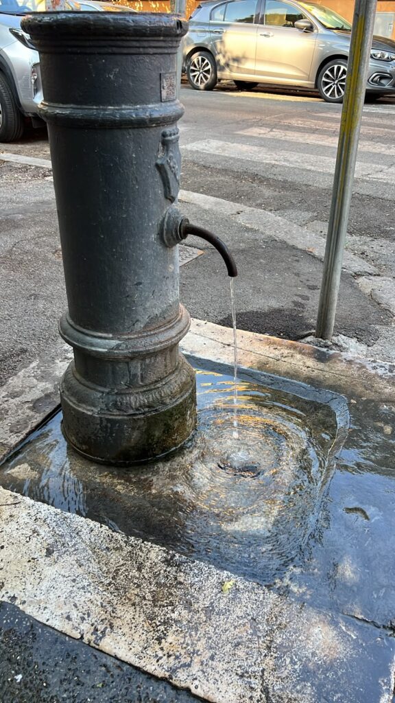 Cast-iron nasone fountain running with drinking water in Rome