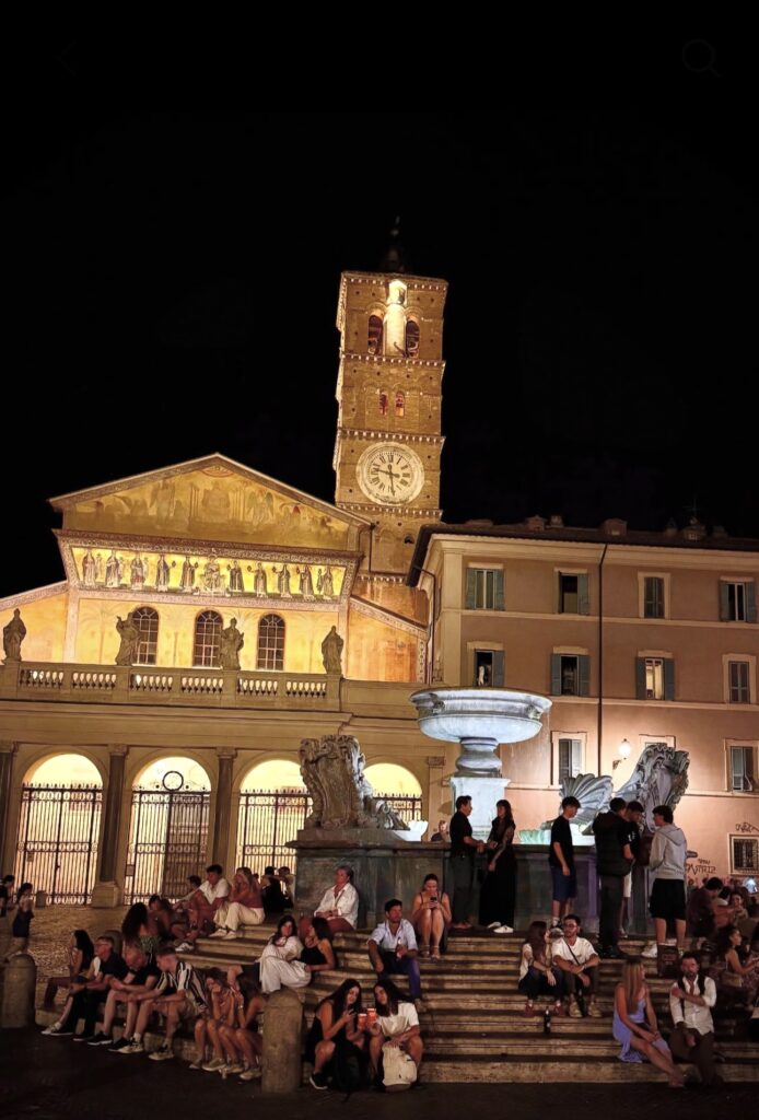 People sitting by a fountain in Trastevere at night