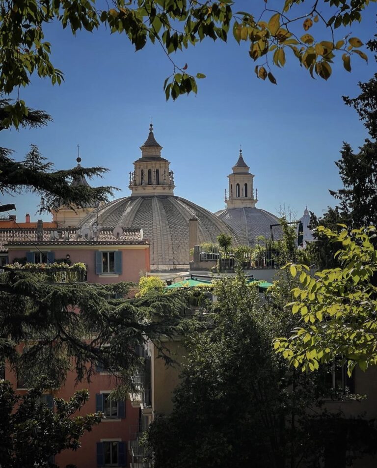 Churches of Piazza del Popolo framed by trees at the end of Via del Corso